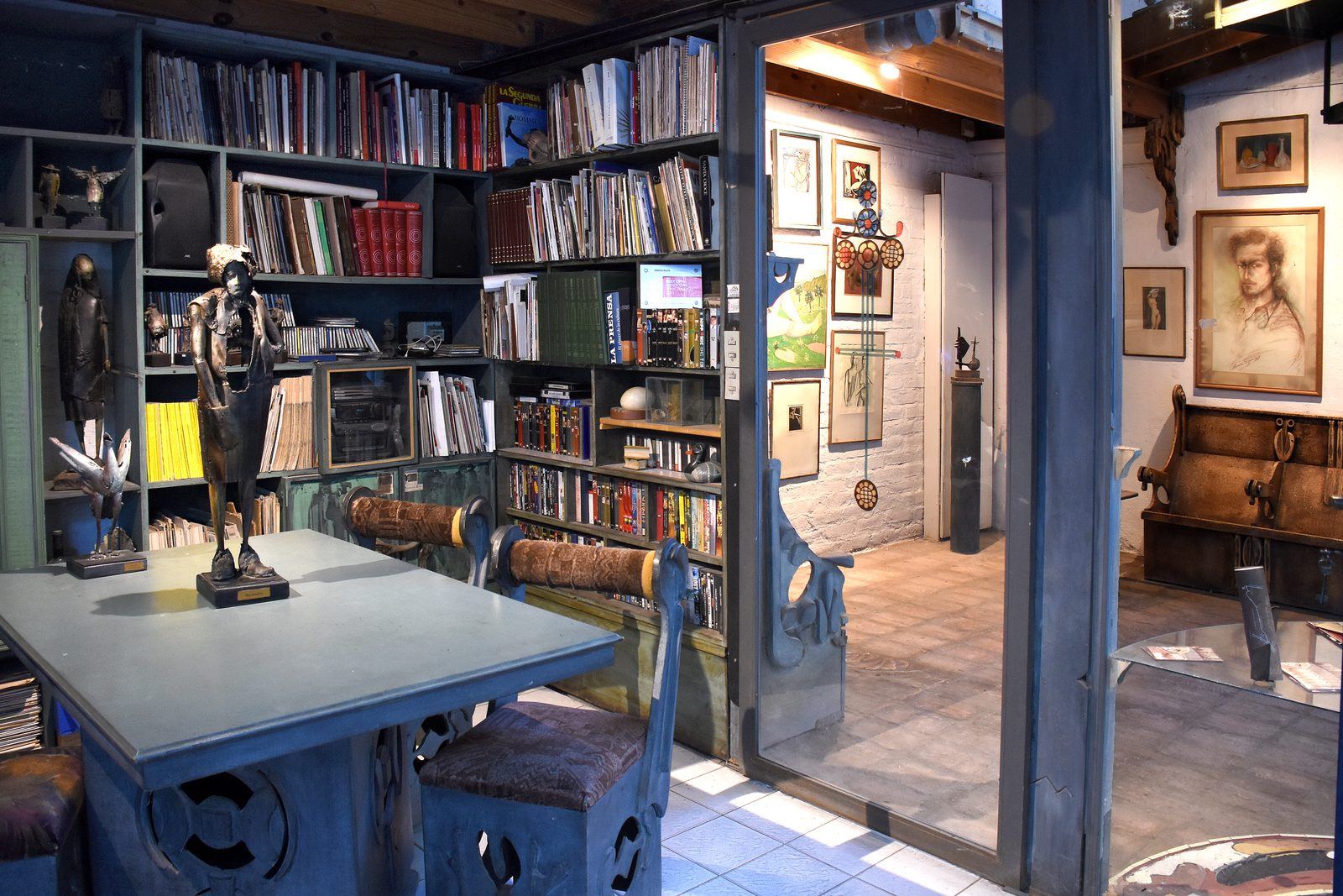 Biblioteca del taller con bronces pequeños, estanterías de libros y una sala de dibujos al fondo