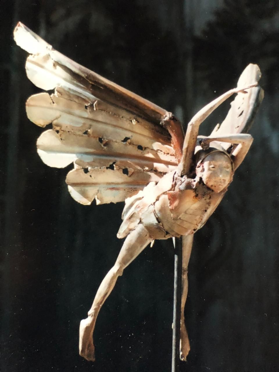 Escultura de un ángel alado en vuelo, con las alas de hierro forjado desplegadas