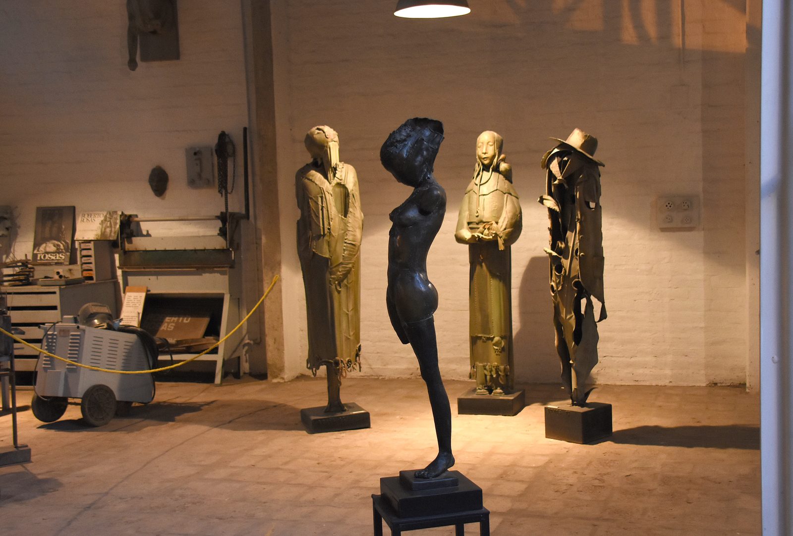 Cuatro esculturas de figuras encapuchadas exhibidas en una sala del taller